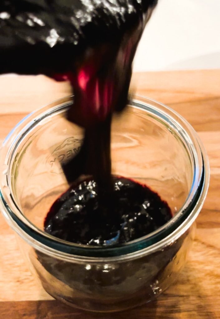 pour freshly cooked blueberry thyme jam into canning jars