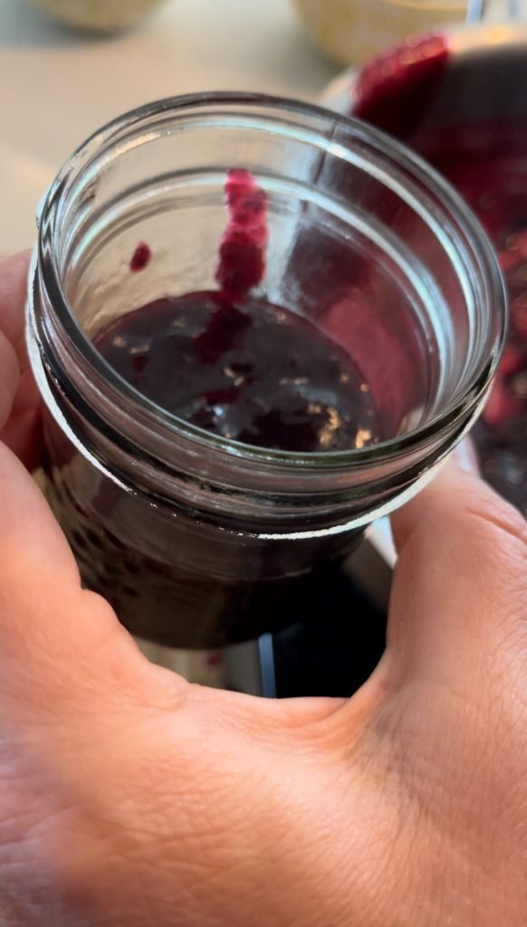 blueberry and blackcurrant jam getting poured into Mason jars