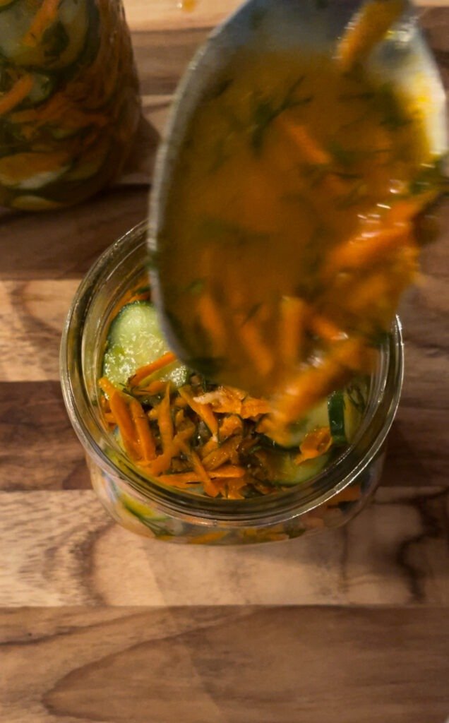 pack pickled cucumber salad into canning jars and top with juices