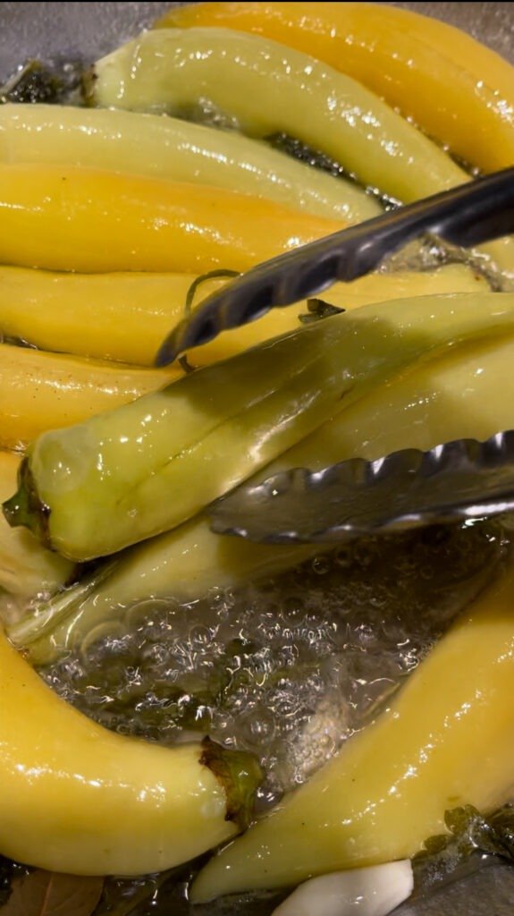 banana peppers getting fried in batches to ensure that they are not overcrowded in a pan