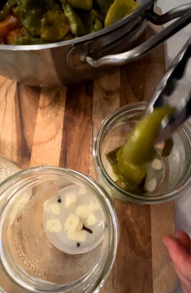 peeled bell peppers gets added to the canning jars on top of the brine