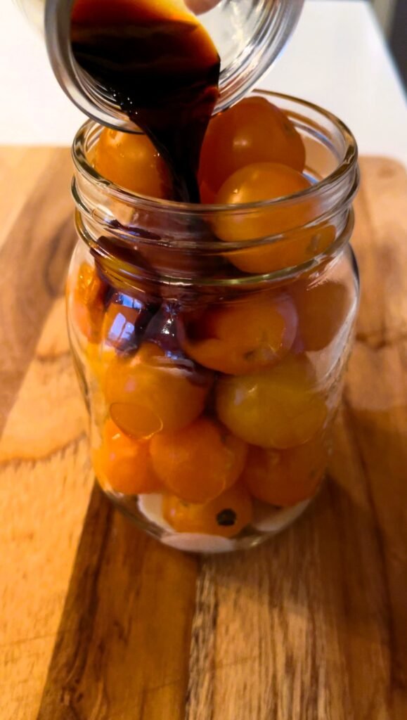 we add soy sauce and vinegar to jar packed with cherry tomatoes, aromatics and spices  