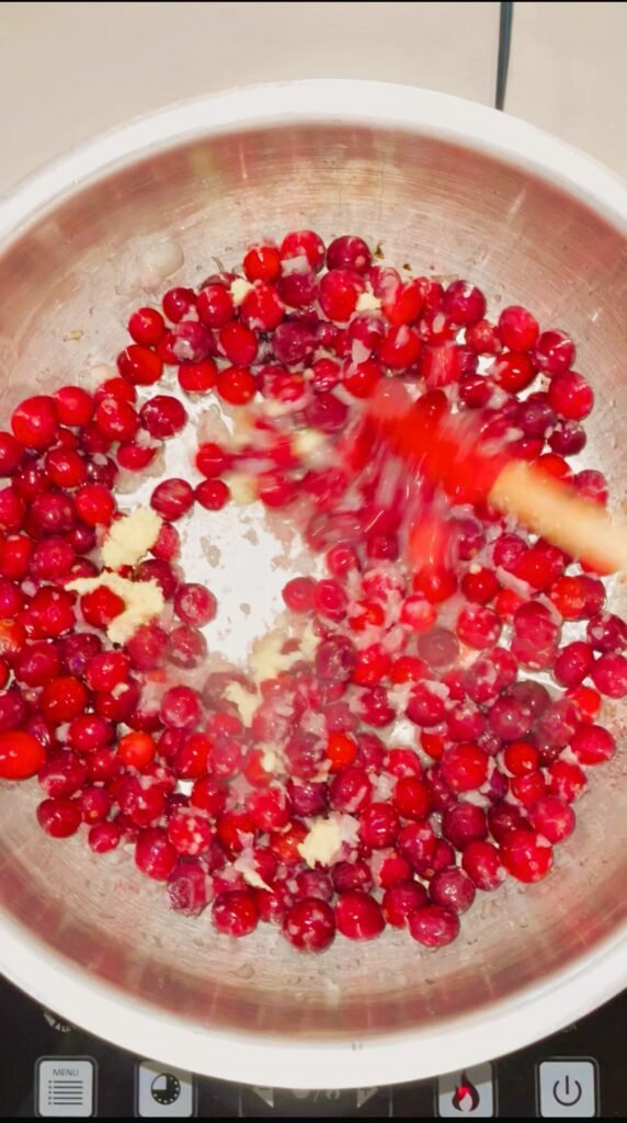 ginger and cranberries are getting added to the pot with fried onions