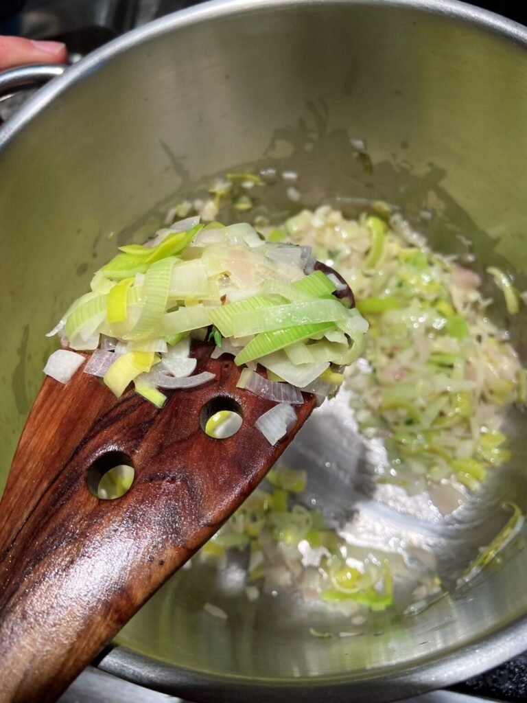 leekds and shallots getting cooked in butter on low heat