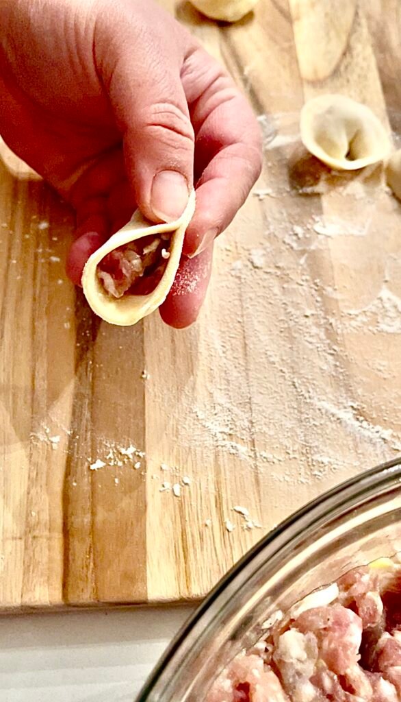 fold the dough over & start pinching from the center of the moonlike shape