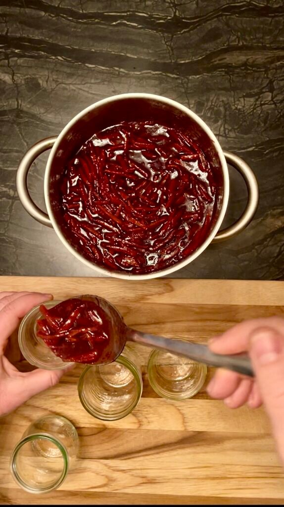 ladle cooked orange marmalade into canning jars