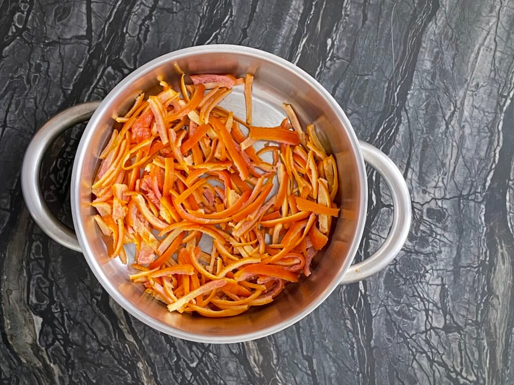 thinly slice orange peel sitting in a heavy-bottomed pot