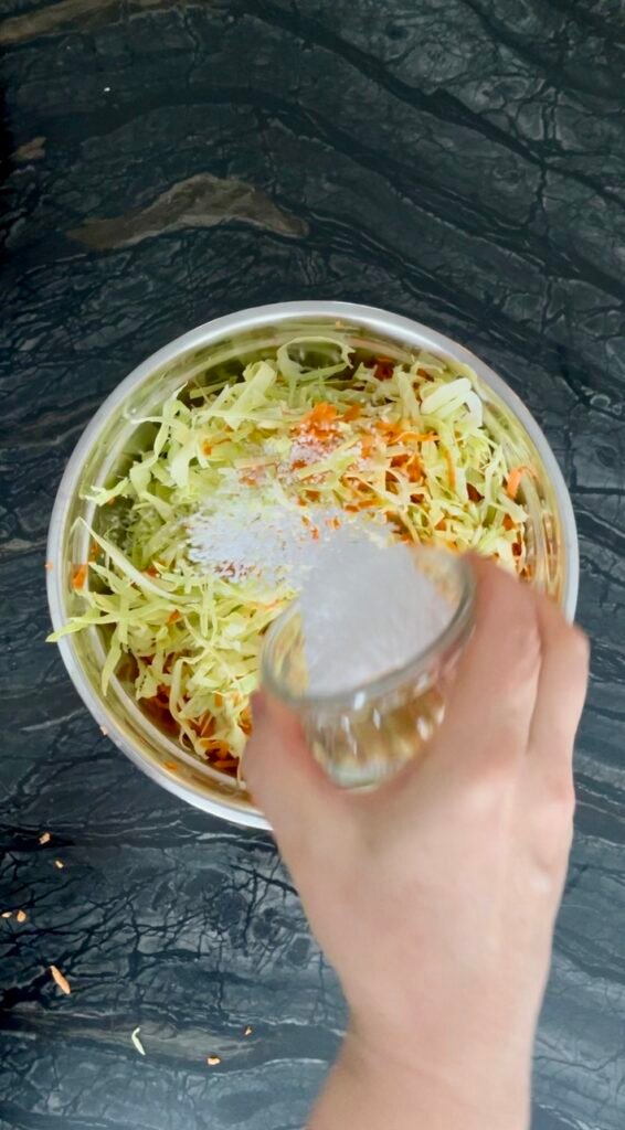 shredded cabbage, grated carrots, salt and sugar combined in a large bowl