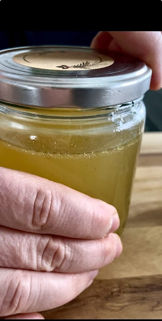 this chicken broth from bones is portioned into glass jars and is ready to go into the freezer for long term storage