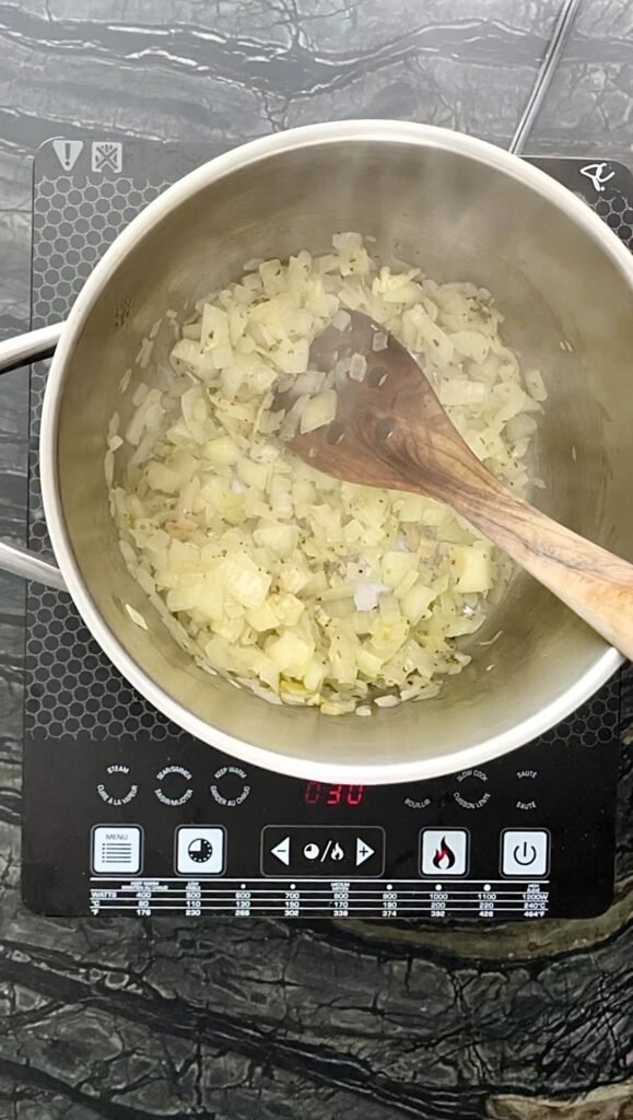 start cioppino base by sweating onions and garli
