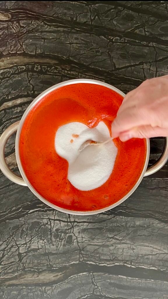 Add sugar mixed with pectin to the red pepper jam mixture