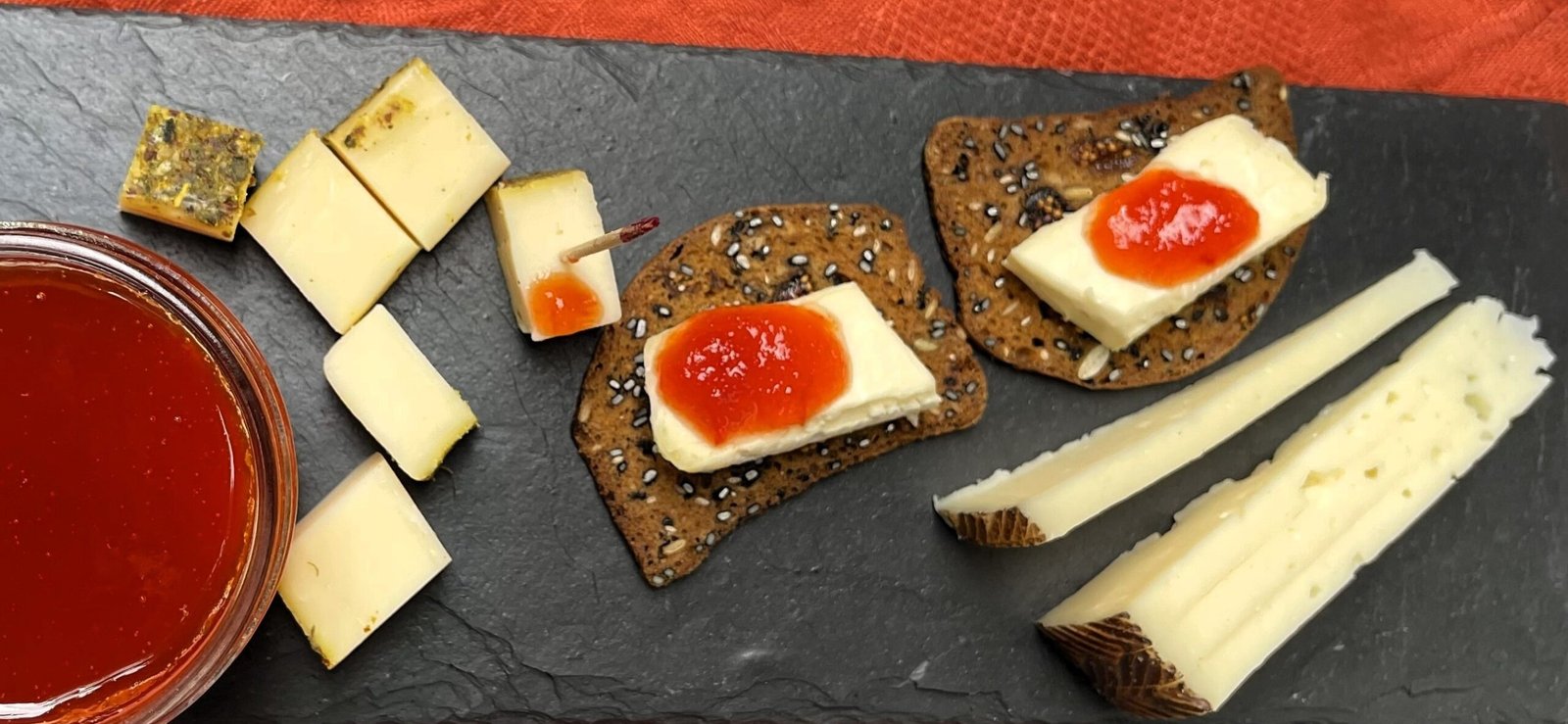 Tomato jam spread on crackers with cheese on a snack board