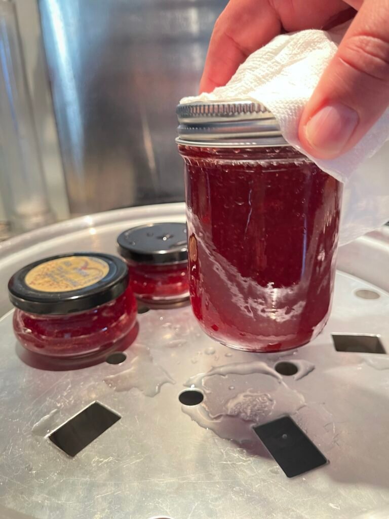 freshly processed huckleberry jam getting picked up from a tray of the atmospheric steam canner