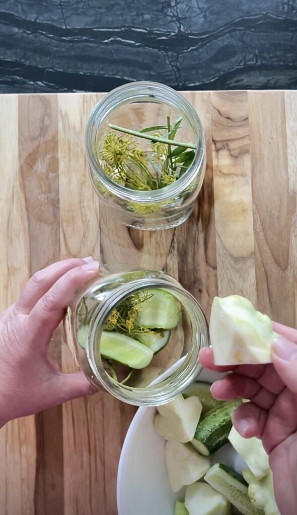 pattypan quarter gets pushed into a jar filled with pattypan and cucumber spears