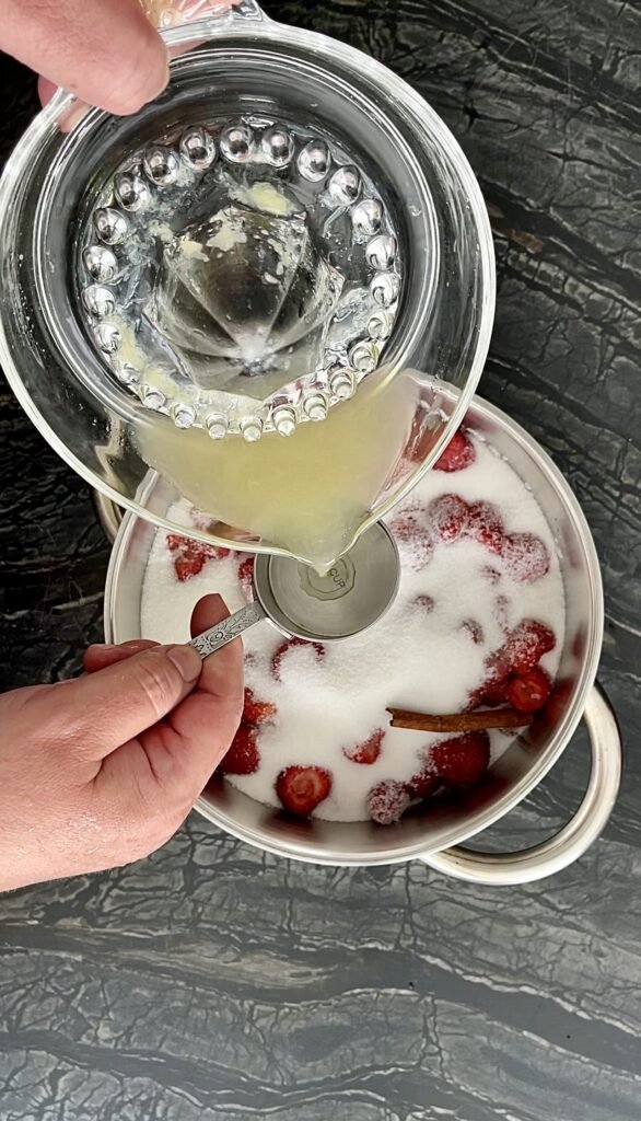 lemon juice gets measured out before being added to the hulled strawberries