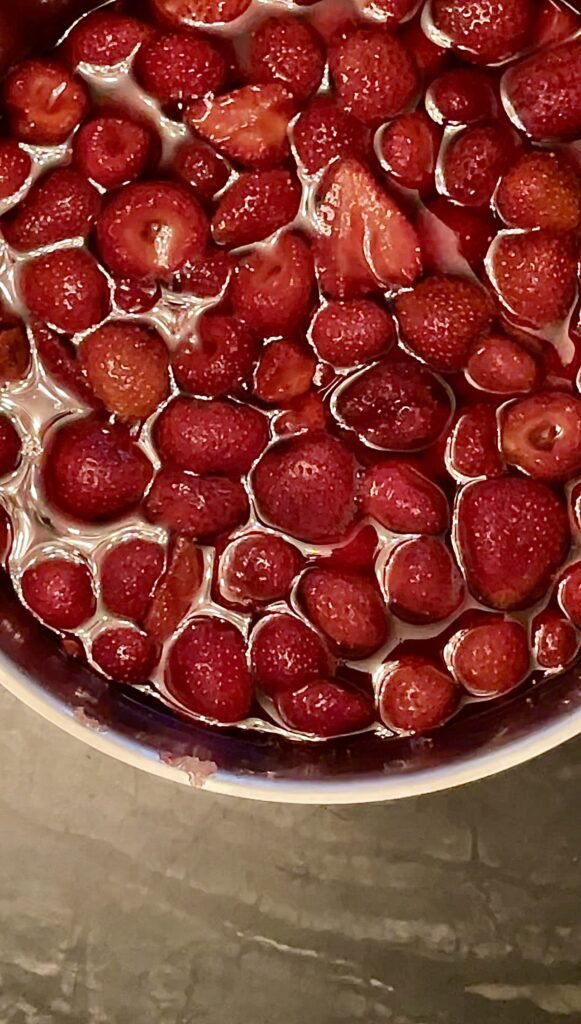 macerated strawberries with the juices are sitting in a pot before we cook them