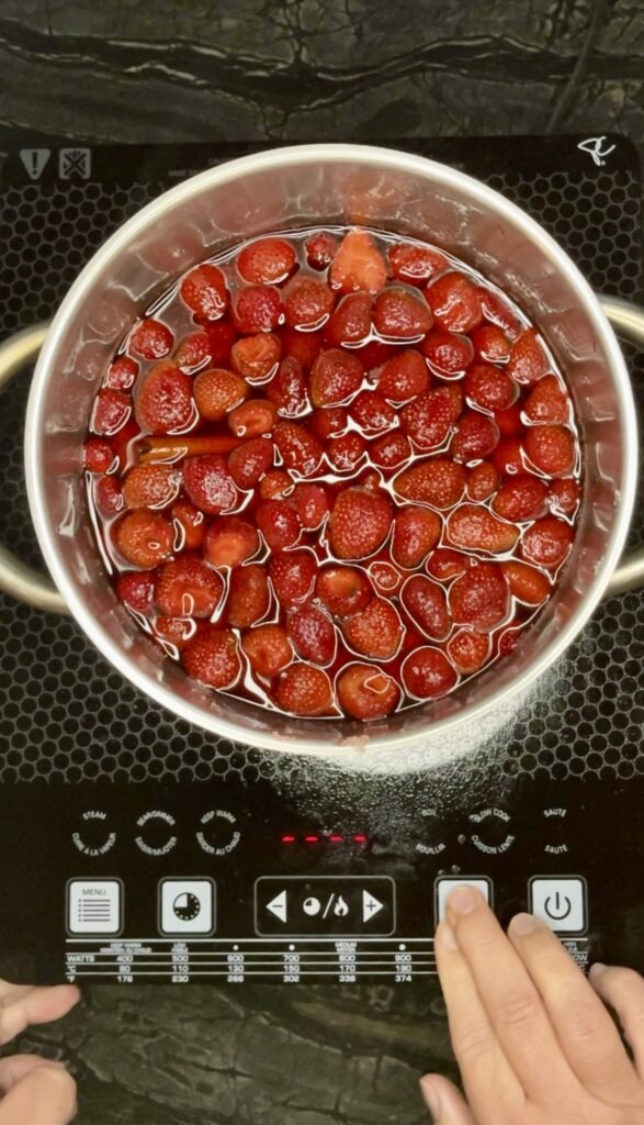 a pot of strawberries on a stove ready for the first round of cooking
