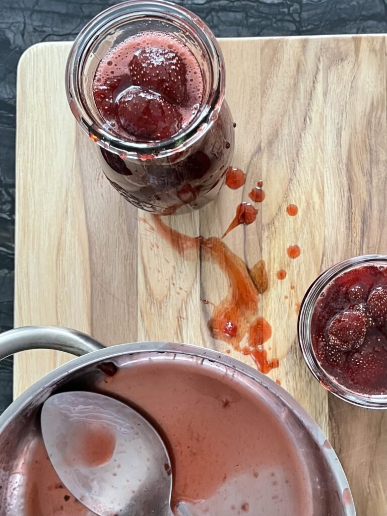 WECK juice jar filled with strawberry syrup with splatters of strawberry syrup around it
