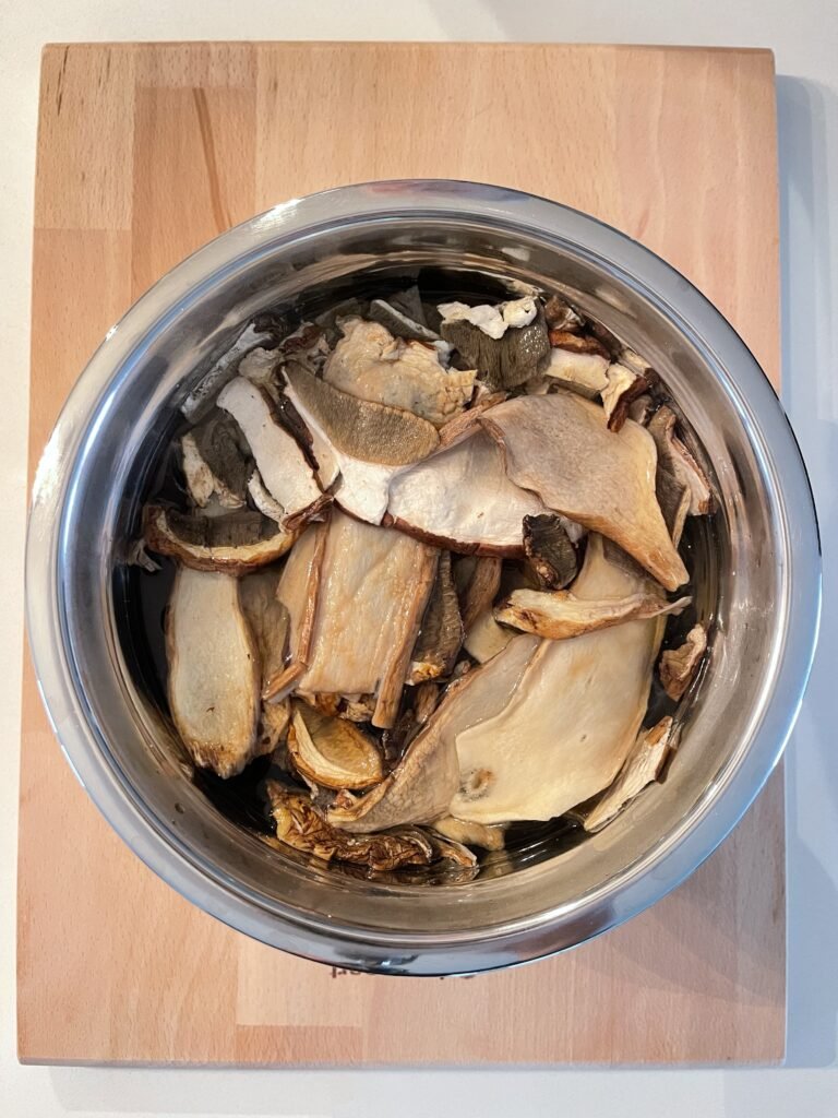 porcini mushrooms soaking in water in a large metal bowl