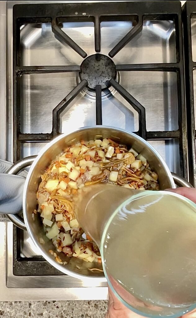 chicken stock gets added to the cooking vegetables and rice