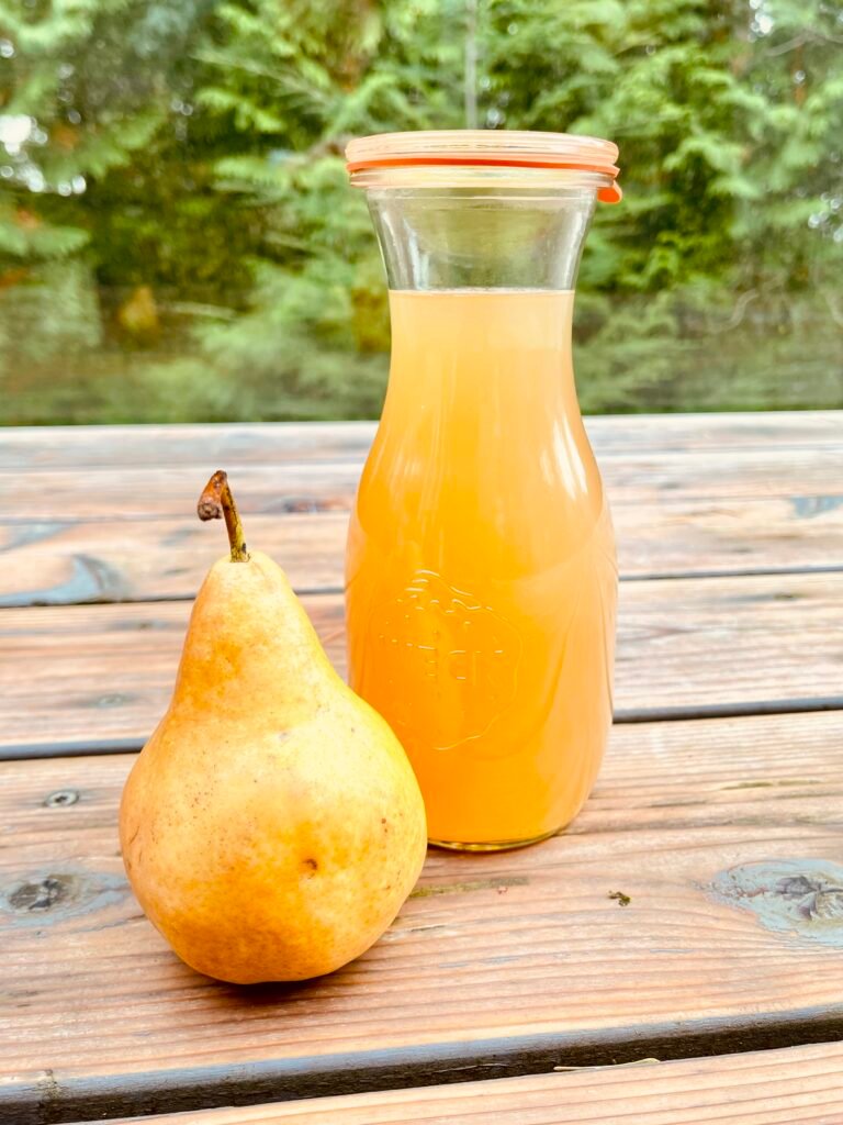 Beautiful amber pear juice in Weck jar on simple wood table