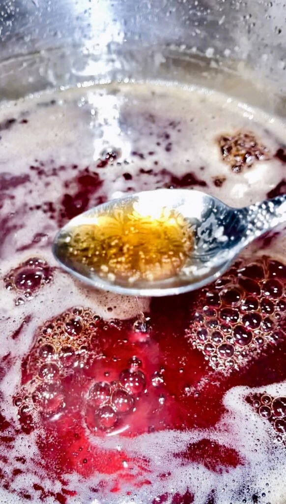 fully cooked pear syrup looks dark burgundy in a pot and dark amber in a spoon