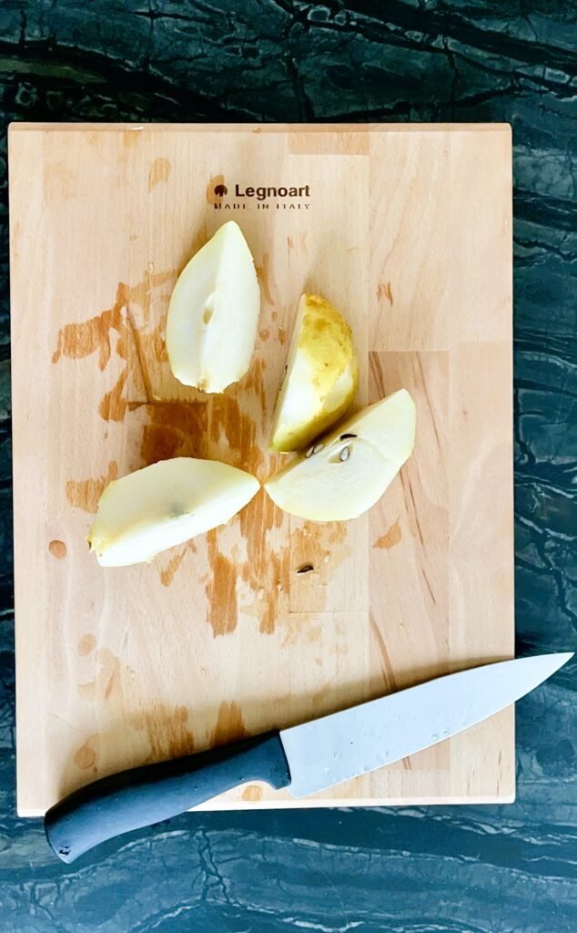 quarter pears with peels and core ready to go into a pot