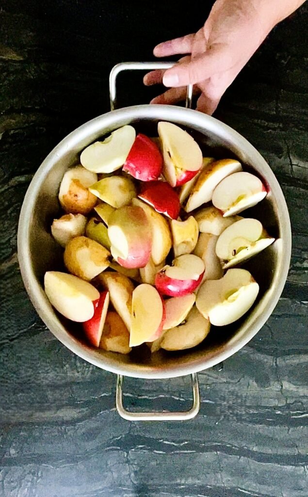 quartered unpeeled apples sitting in a large metal pot