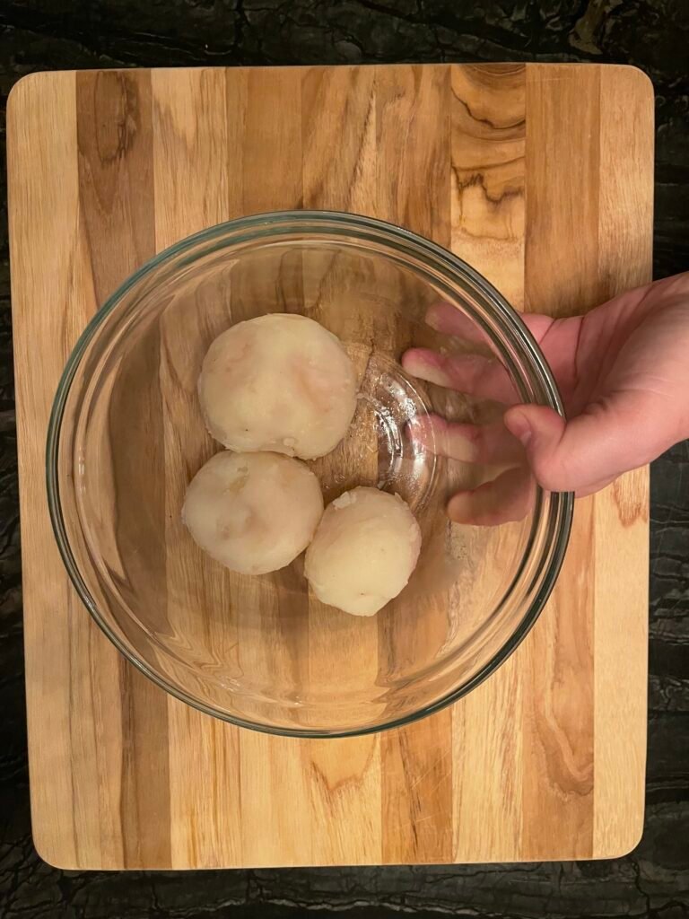 peeled wholed potatoes in a glass bowl ready to be added to the pasta filling
