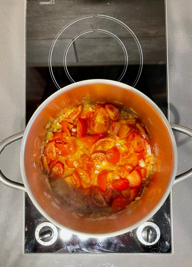 We add roasted bell pepper and tomatoes to he pot next.