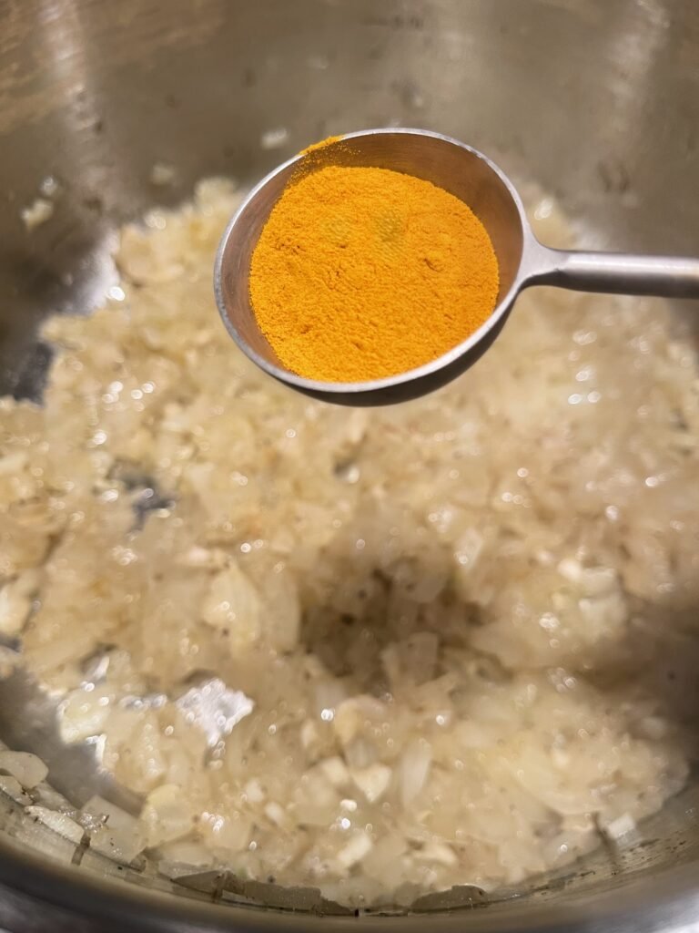 one tablespoon of turmeric is ready to be added to the pot with the cooking onion-garlic mixture