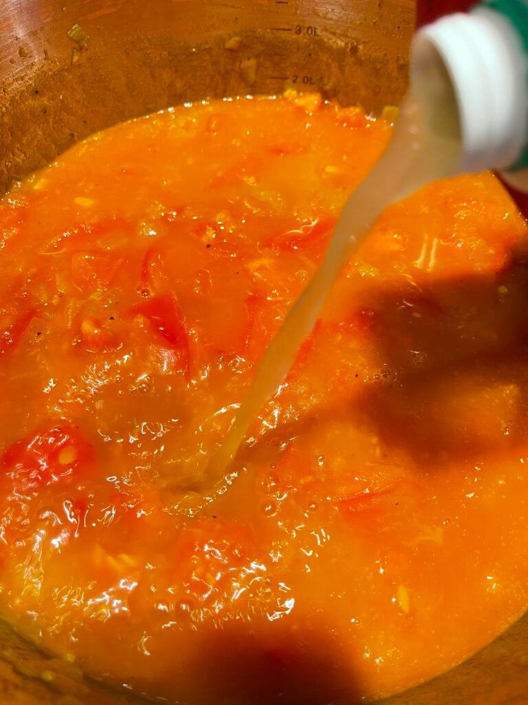 chicken stock gets poured in into pot with the cooking veggies
