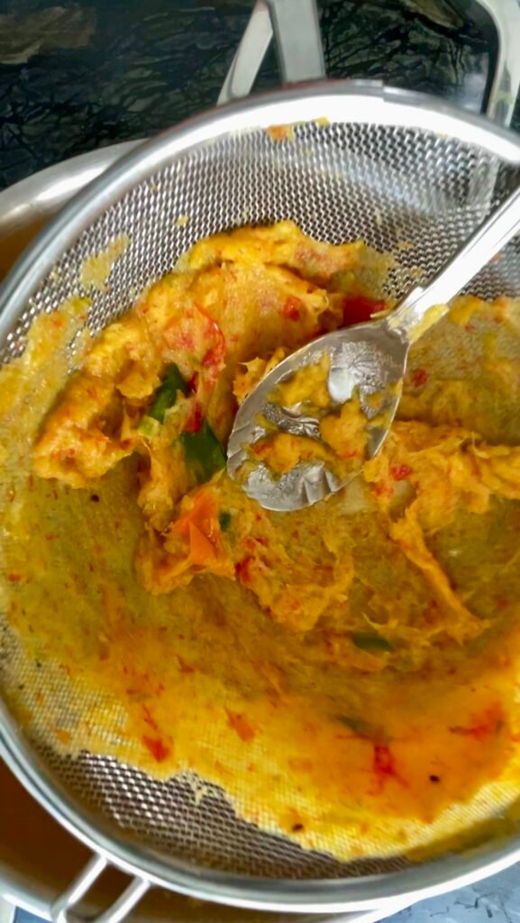 hot pepper jam prep - press pineapple and pepper pulp leftovers through a metal strainer