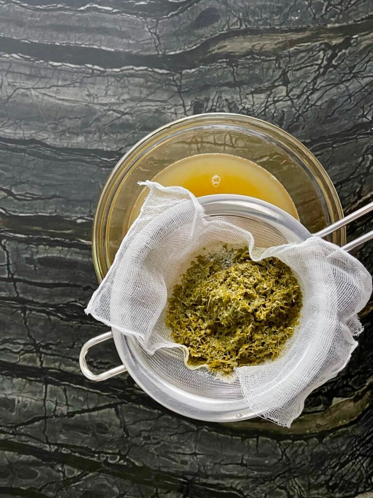 Apple lemon balm jelly straining through cheesecloth for clear result