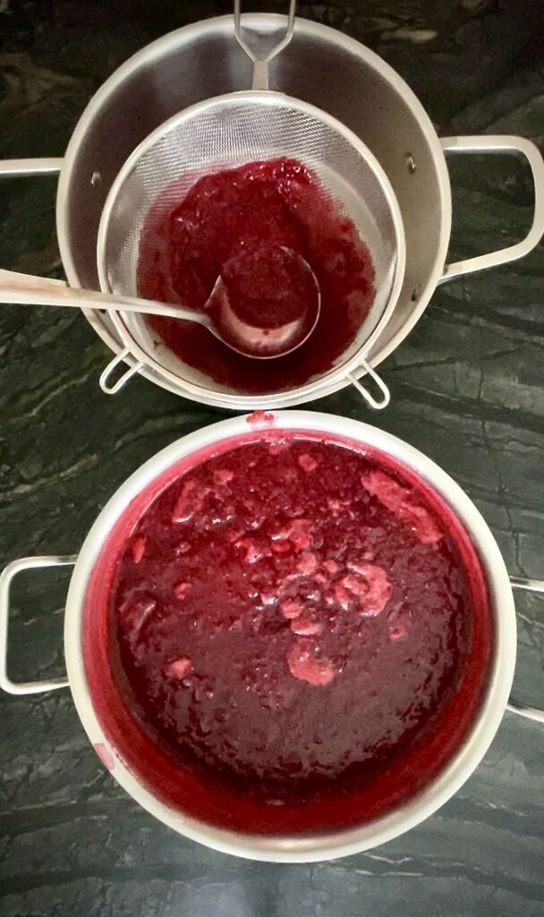 pushing raspberry pulp through a fine-mesh sieve