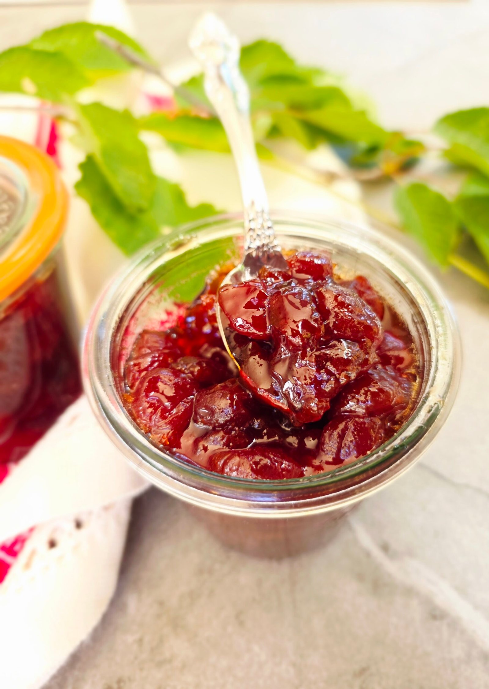 spoon lifting sour cherry jam from a glass jar