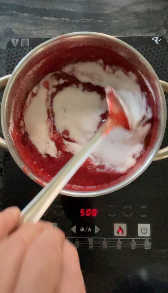 Spoon stirring sugar and pectin into cooking strawberry lime jam