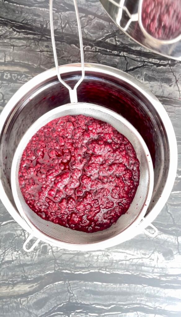 Strained blackberry pulp sitting in a fine mesh sieve
