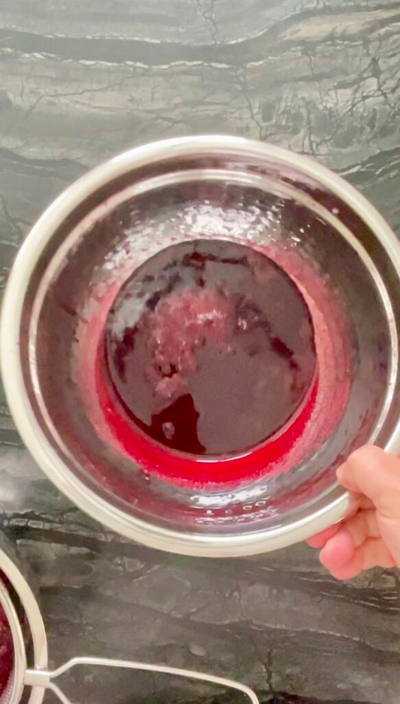 Strained berry juice sitting in a metal bowl