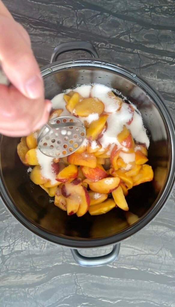 peach apricot lavender jam: mashing the peach chunks with the first cup of sugar