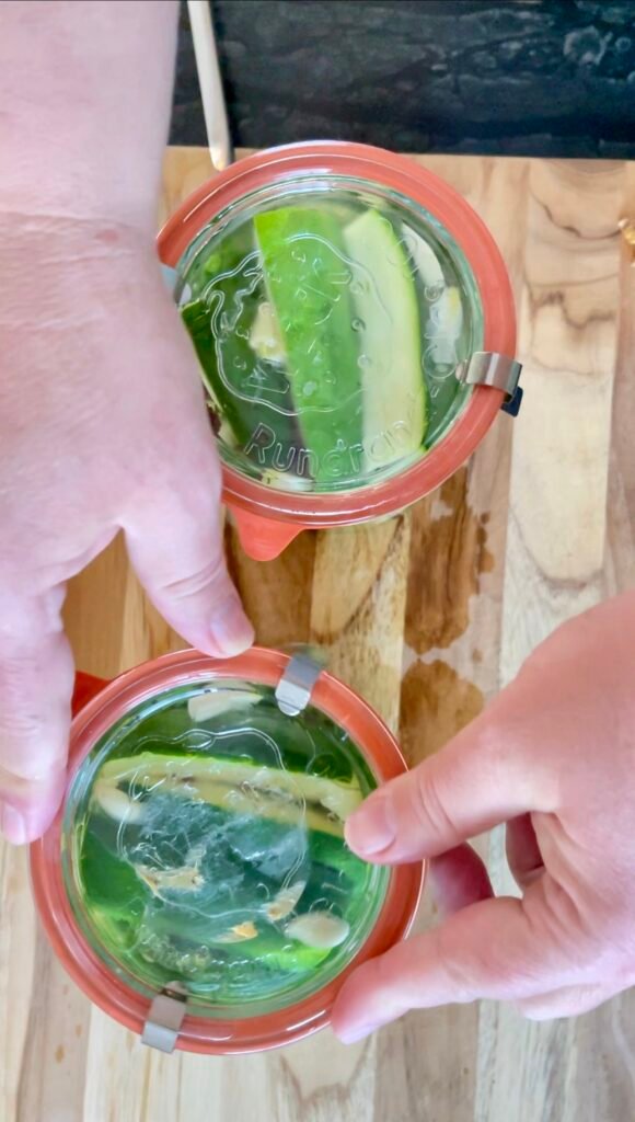Hands sealing WECK jars of zucchini pickles with lids