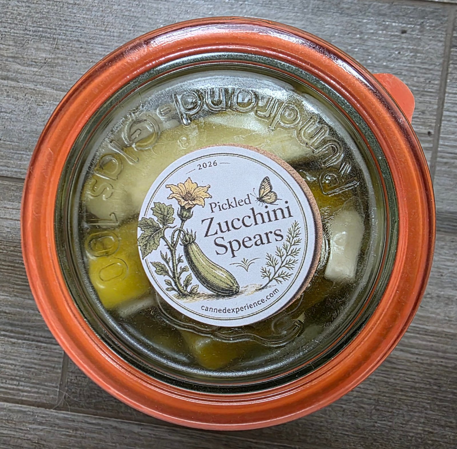 Finished jar of pickled zucchini spears with a custom canning label