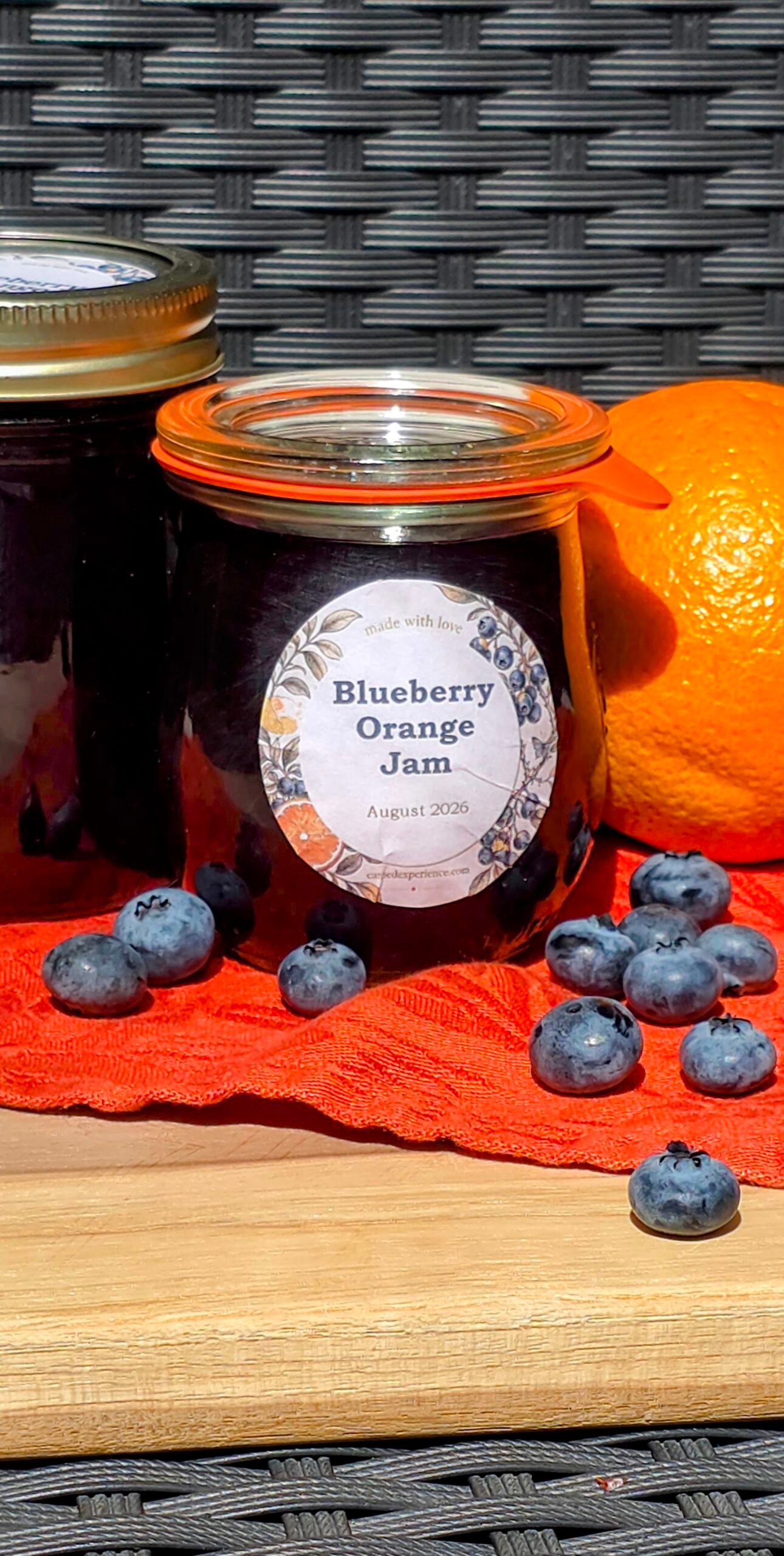 A jar of homemade blueberry orange jam with fresh blueberries and an orange beside it