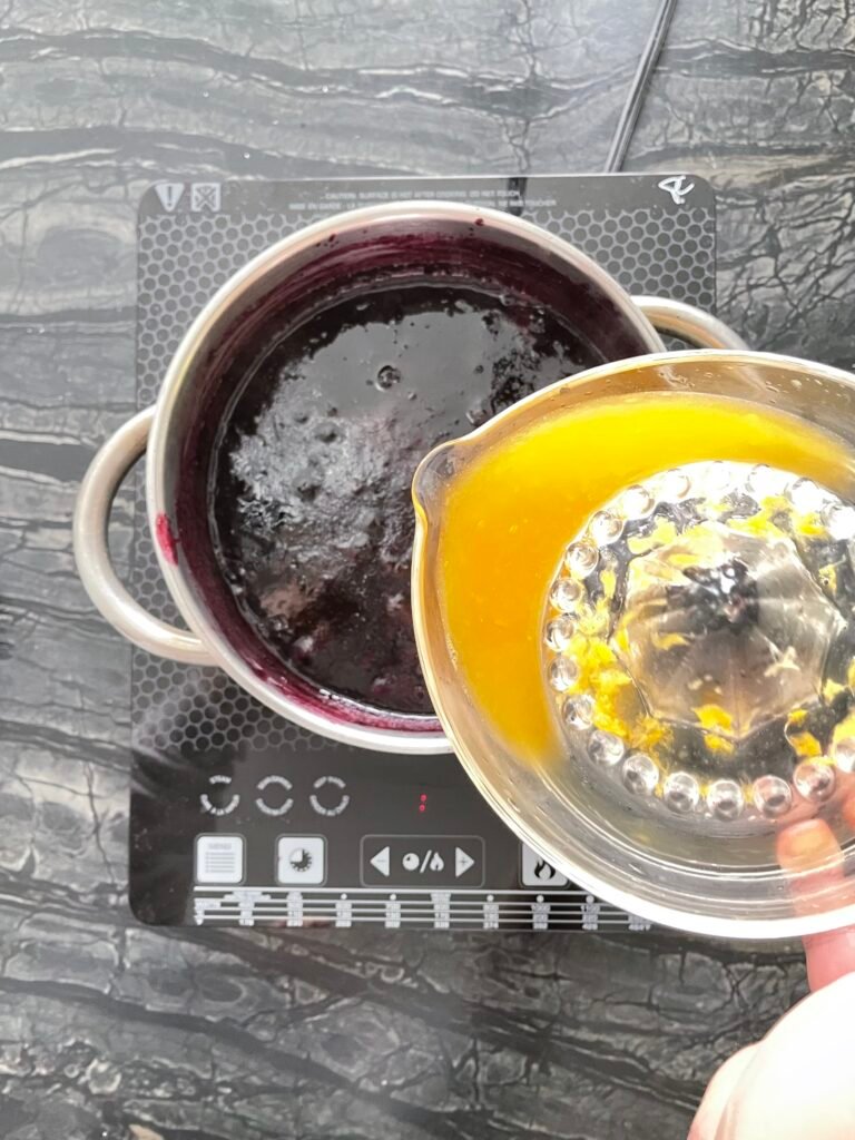 Making Blueberry Orange Jam — squeezing orange juice into the pot