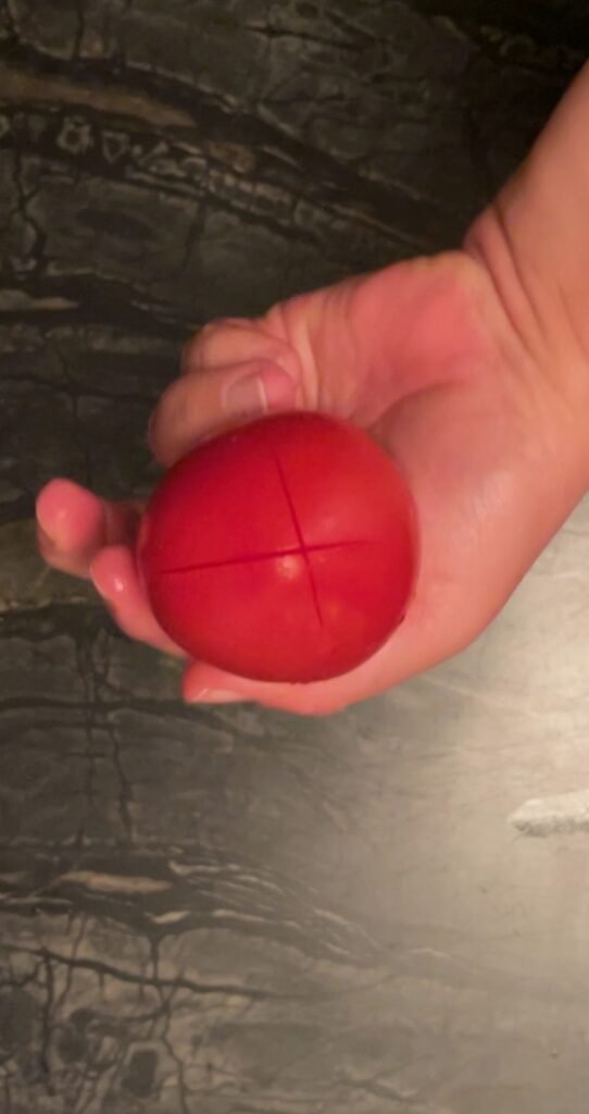 Tomato jam scoring an X into a tomato for easy peeling