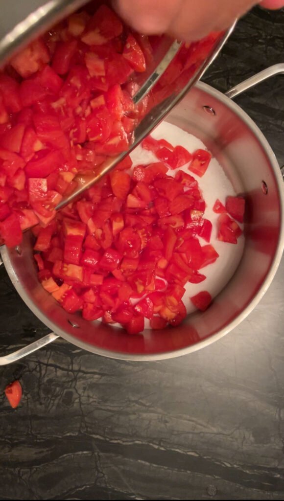 Tomato jam diced tomatoes going into a pot with sugar and salt