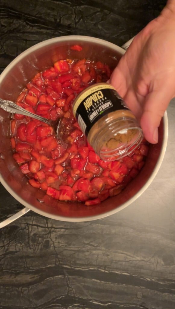 Tomato jam adding a spoonful of ground cumin