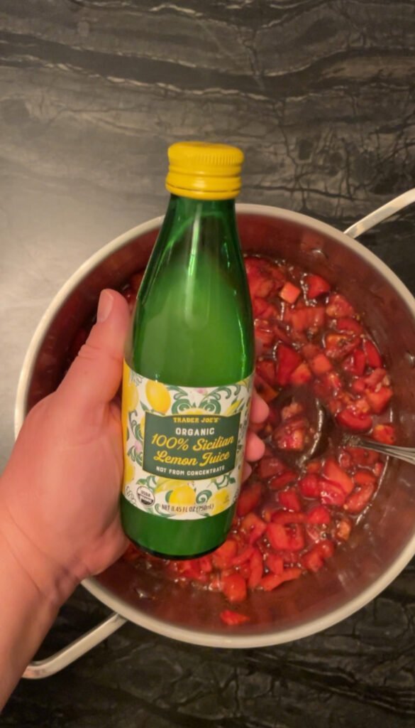 Tomato jam pouring bottled lemon juice into diced tomatoes
