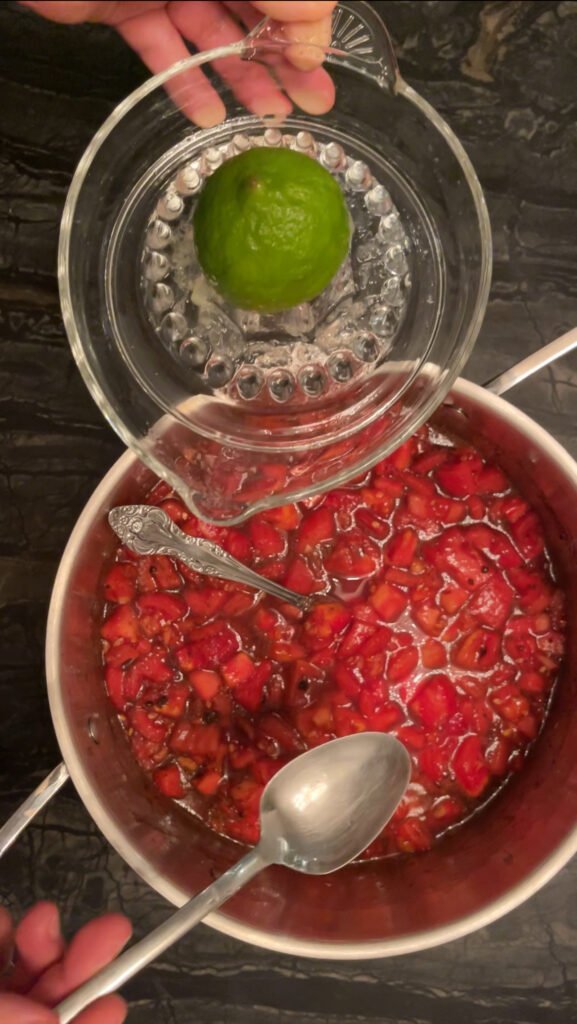 Tomato jam diced tomatoes in a pot with lime juice being poured in