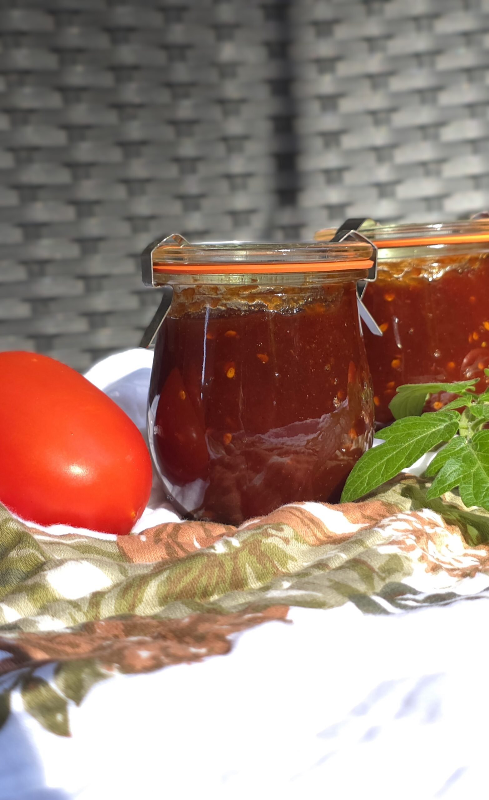 Tomato jam finished jars beside fresh whole tomatoes